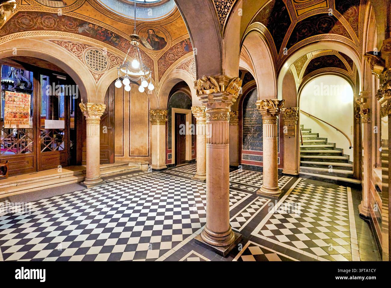 Marmorsäulen mit vergoldeten Kapitellen und frescoierten Gewölben über einem karierten Boden in einer byzantinischen Renaissance-Kircheingangshalle in Wien, Österreich Stockfoto