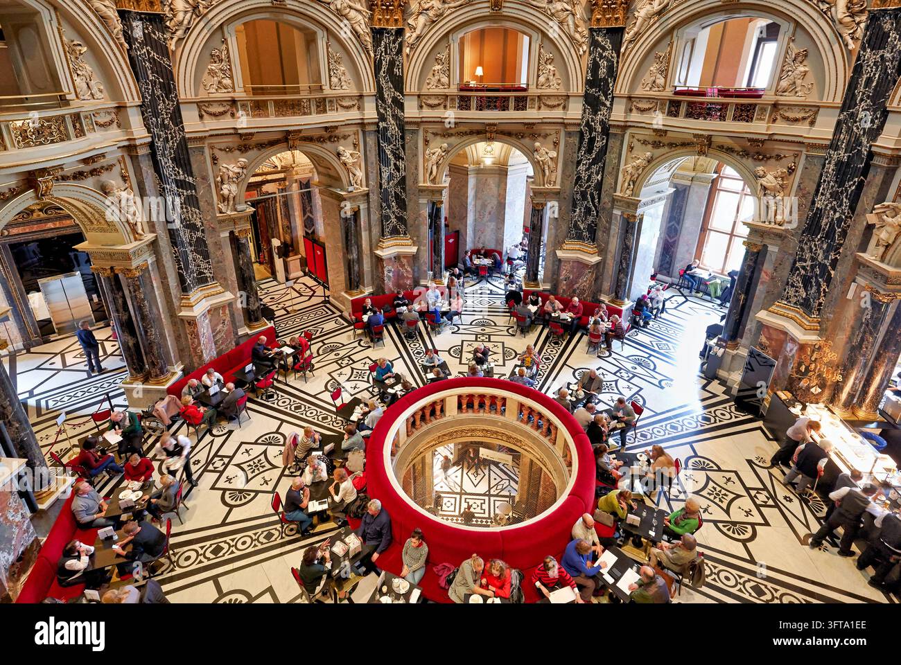 Hohe Blickwinkelansicht von Besuchern an Café-Tischen in der Kuppelhalle des Kunsthistorischen Museums in Wien, Österreich, mit Marmorsäulen und kunstvollem Dekor. Stockfoto