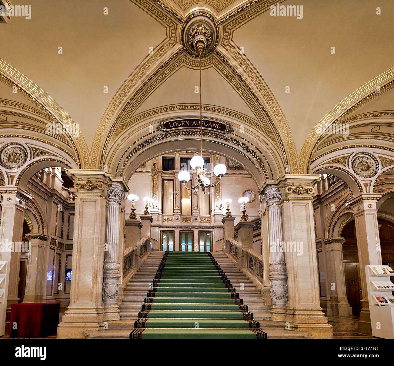 Grünteppich-belegte Marmortreppe unter einer vergoldeten gewölbten Decke der Wiener Staatsoper, die zum Logen-Aufgang-Eingang führt. Stockfoto