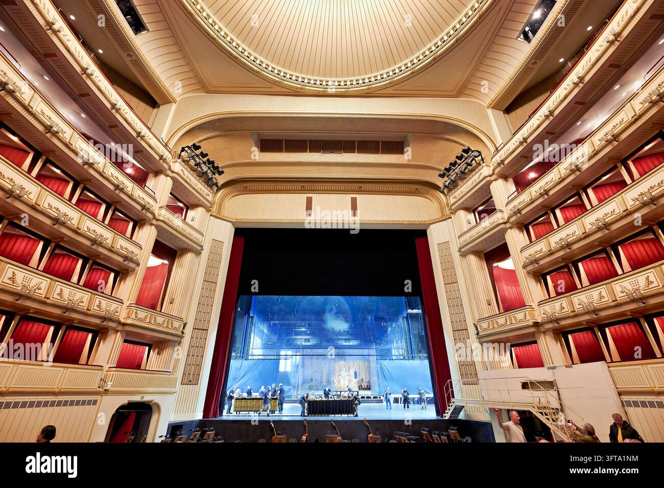 Bühnenmitarbeiter bereiten die Kulisse vor, während Besucher die vergoldeten Ränge mit roten Vorhängen in der Wiener Staatsoper in Wien betrachten Stockfoto