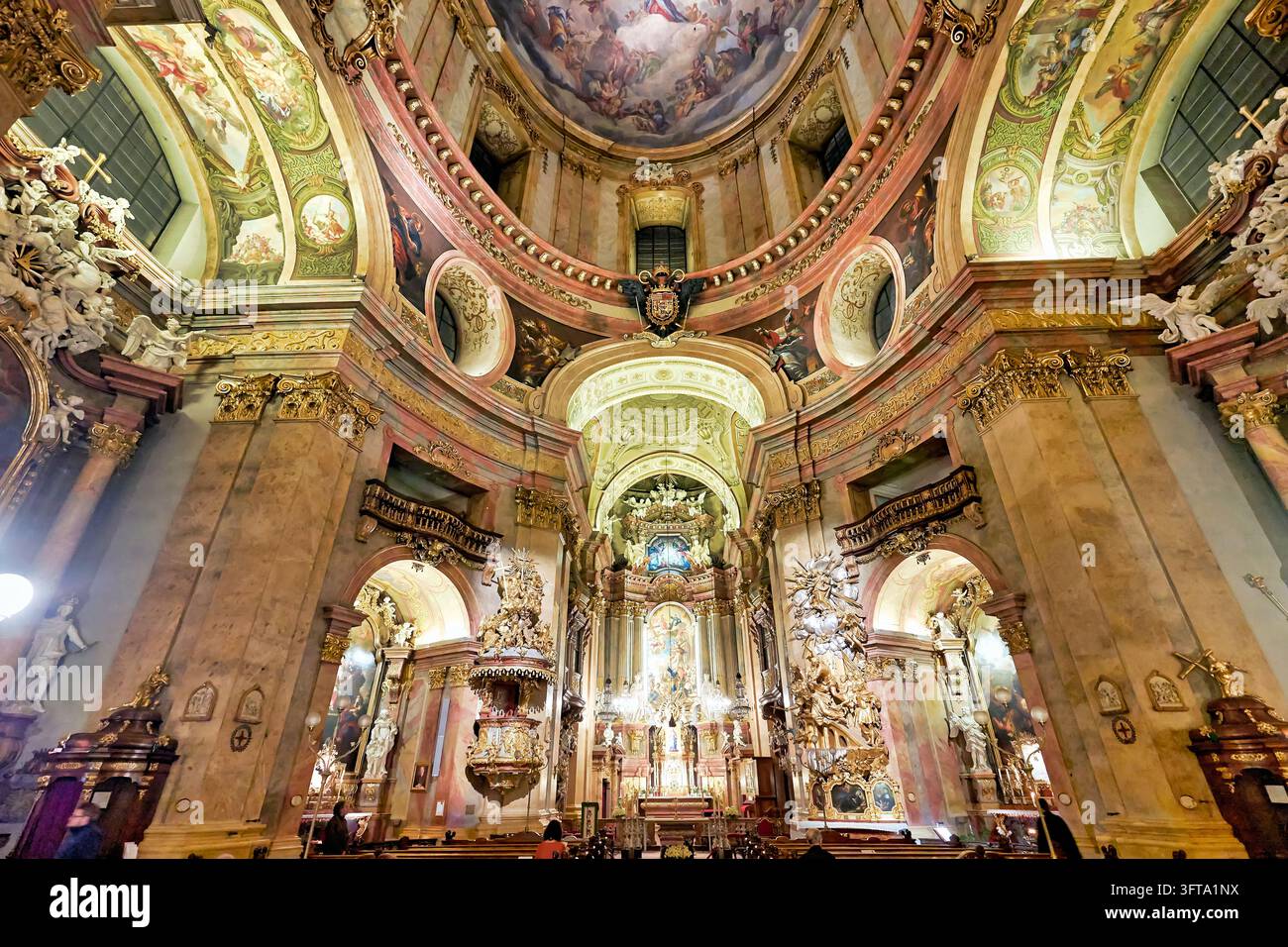 Breitwinkelaufnahme des vergoldeten Hochaltars, der Kanzel und der Kuppelfresken in der Peterskirche, einer römisch-katholischen Kirche in der Inneren Stadt Wiens. Stockfoto