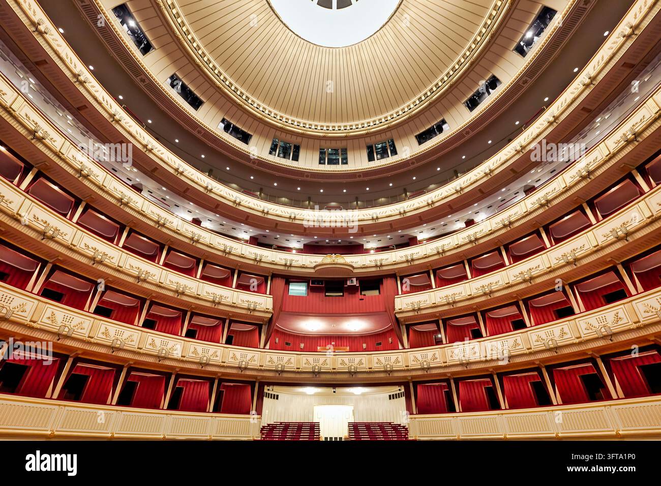 Niedrigwinkelaufnahme leerer roter Kisten und vergoldeter Balkone, die sich in Stockwerken zur Decke der Wiener Staatsoper in der österreichischen Hauptstadt erheben. Stockfoto