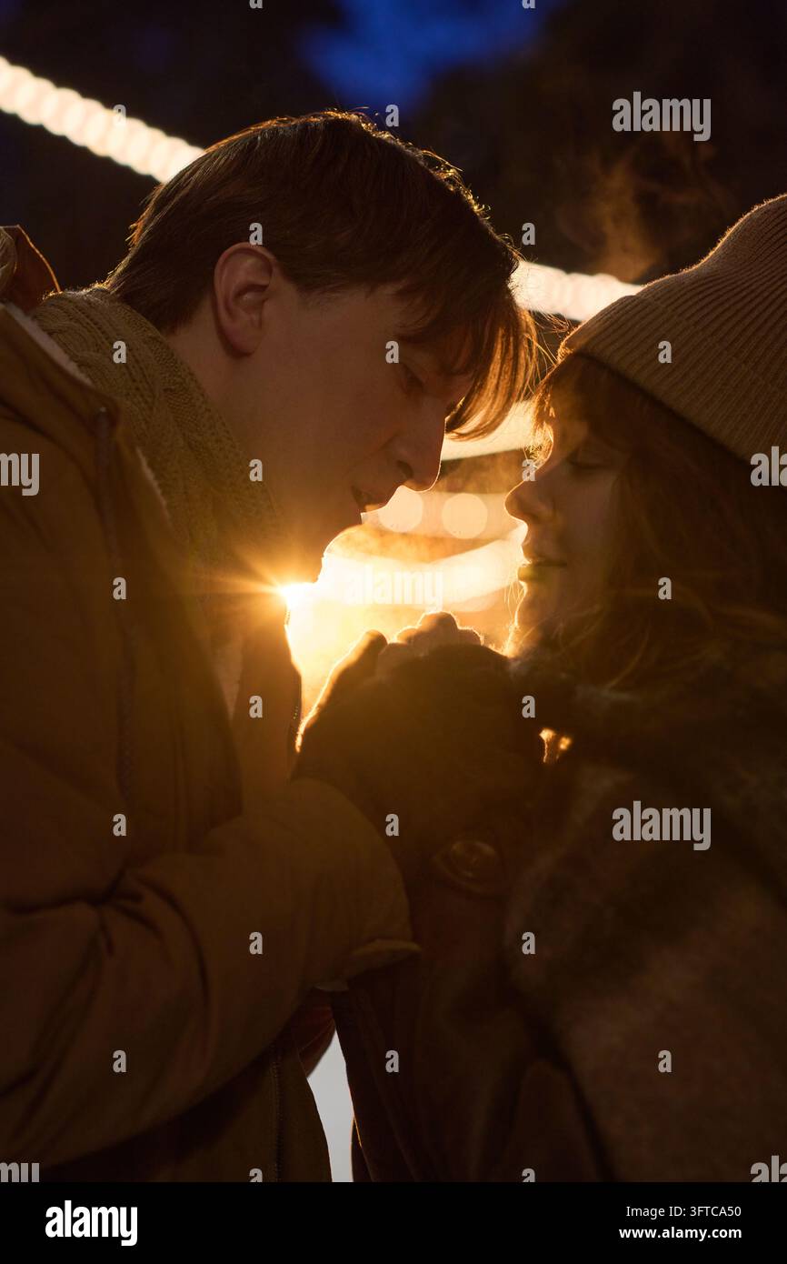 Romantisches Paar, das sich an einem Winterabend im Freien die Hände wärmt Stockfoto