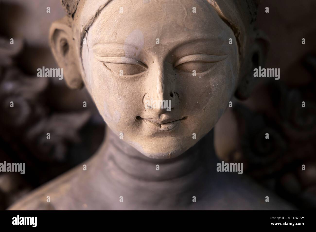 Makroansicht eines glatten Ton-Göttergesichts mit geschnitzten Augenlidern und einem sanften Lächeln im Bezirk Kumartuli, Westbengalen, Kalkutta, Indien Stockfoto