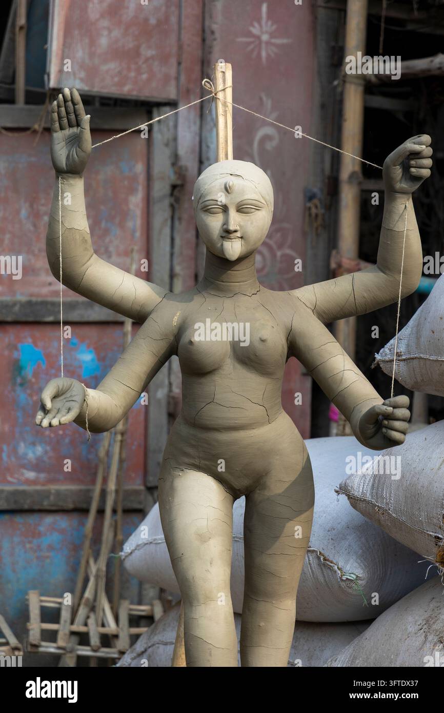 Rohe Tonstatue mit erhobenen Armen und Rissen, die an Schnüren zum Trocknen an einer Straßenecke im Bezirk Kumartuli in Westbengalen, Kalkutta, Indien aufgehängt ist Stockfoto