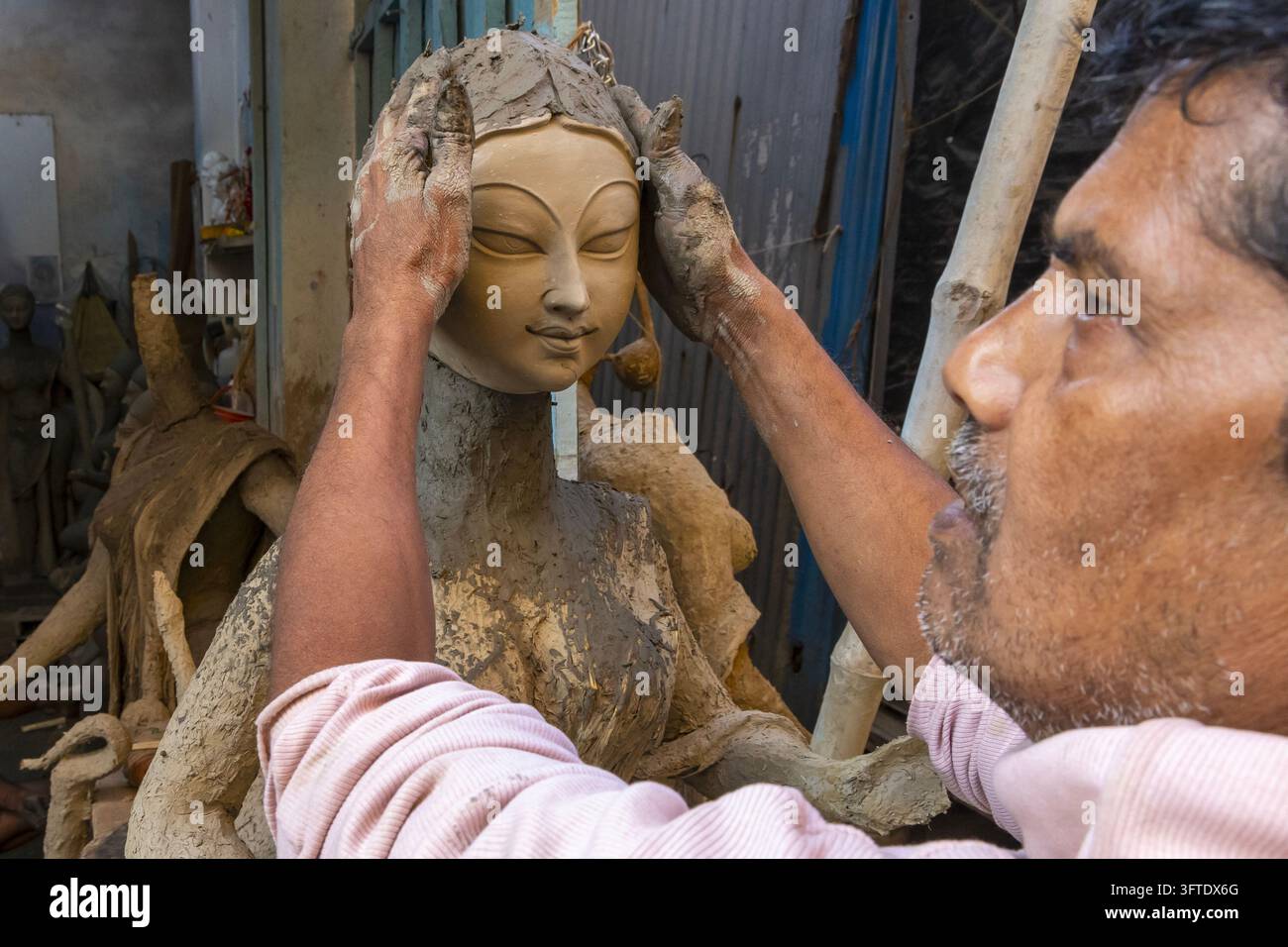 Nahaufnahme eines älteren Handwerkers, der den Kopf einer Statue in einer engen Werkstatt im Bezirk Kumartuli, Westbengalen, Kalkutta, Indien, formt Stockfoto
