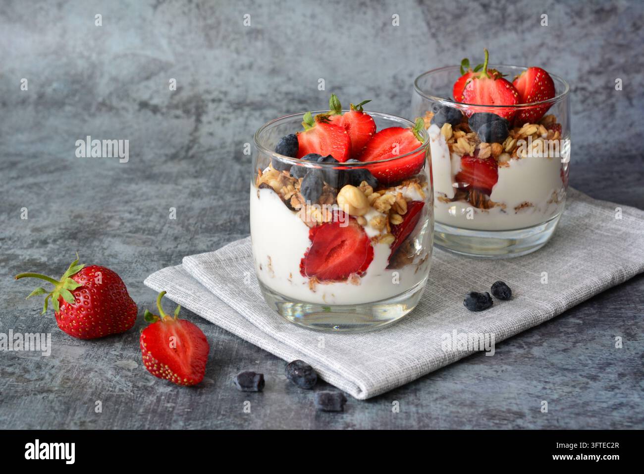 Erdbeer- und Blaubeer-Yoghurt-Parfait mit Granola auf Steintisch, Kopierraum Stockfoto