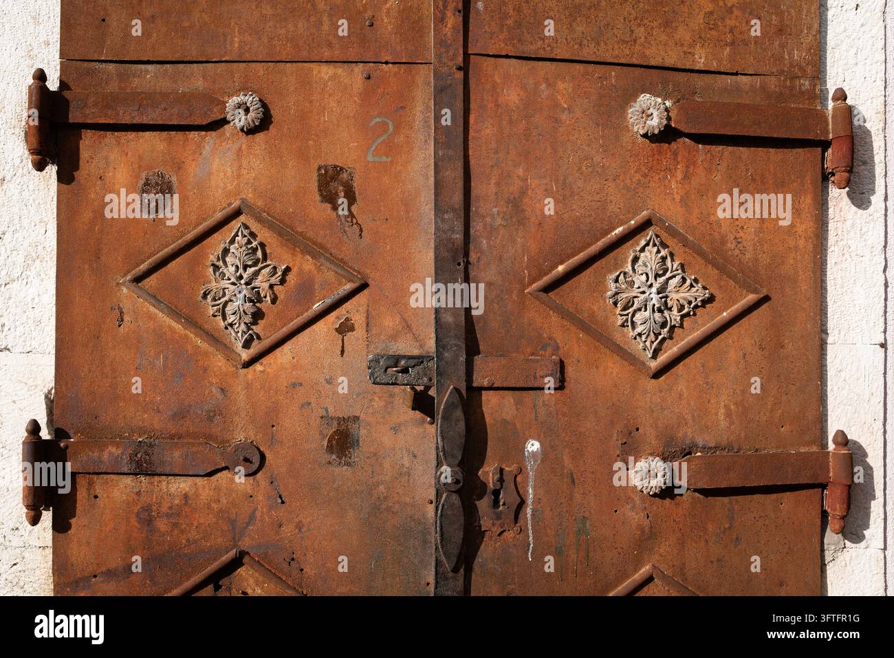 Sonnenbeschienene rostige Ziergittertür mit Blumendetails in Mostar, Bosnien und Herzegowina Stockfoto