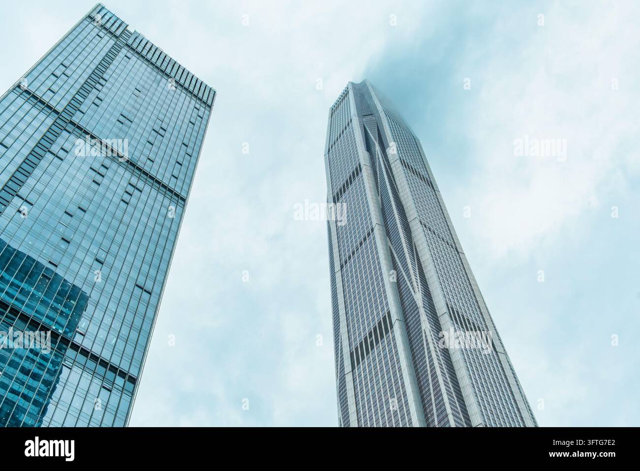 Niedrigwinklige Ansicht von Glas-Hochhäusern, die in niedrige Wolken in der Stadt Shenzhen, China, aufragen. Moderne Hochhäuser, Geschäftsviertel, Unternehmen Stockfoto