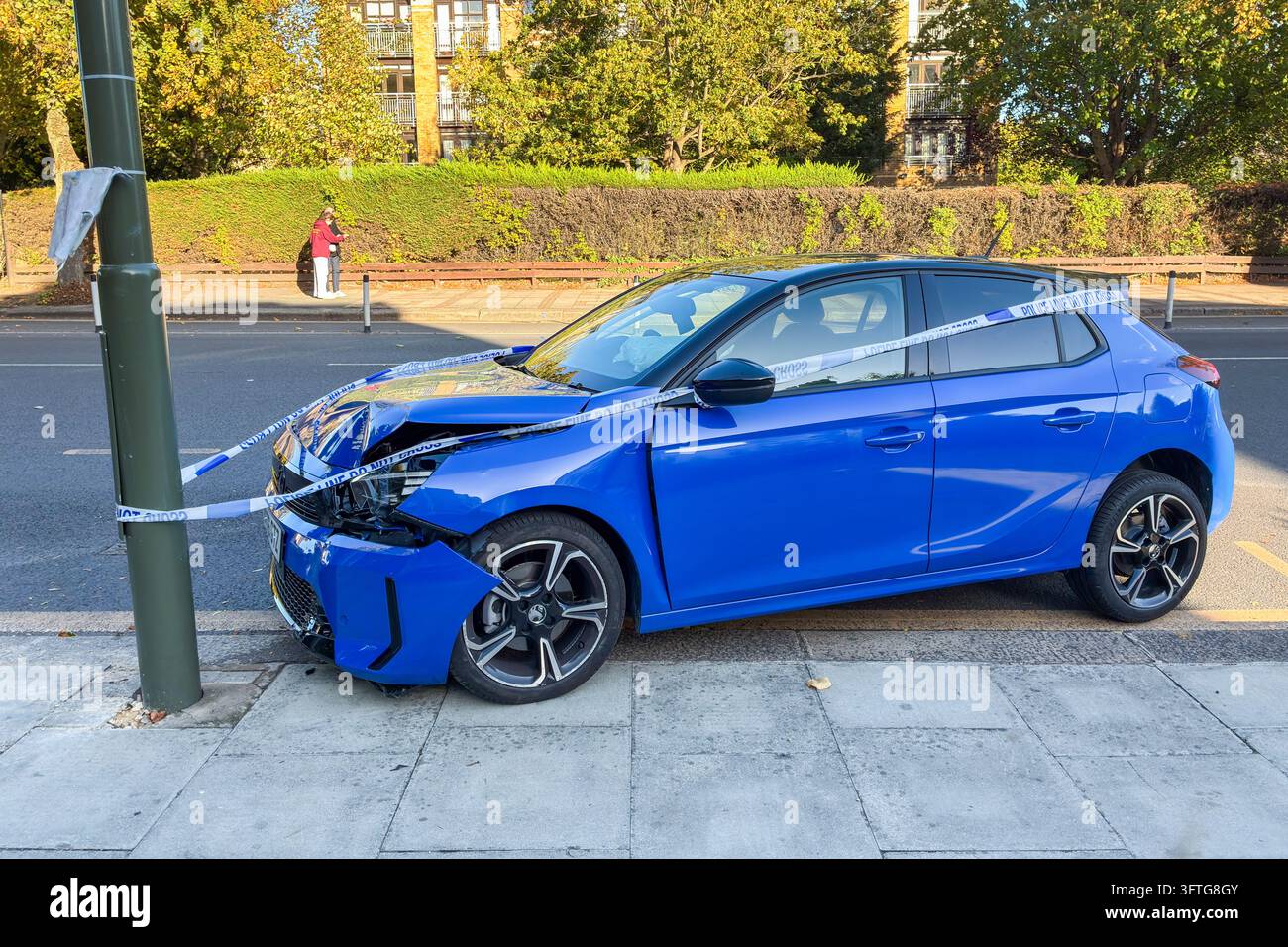 Ein blauer Vauxhall Corsa Kombi mit Frontschadenschaden und einem in Polizeiband eingewickelten Laternenpfahl, Nordlondon, UK Stockfoto