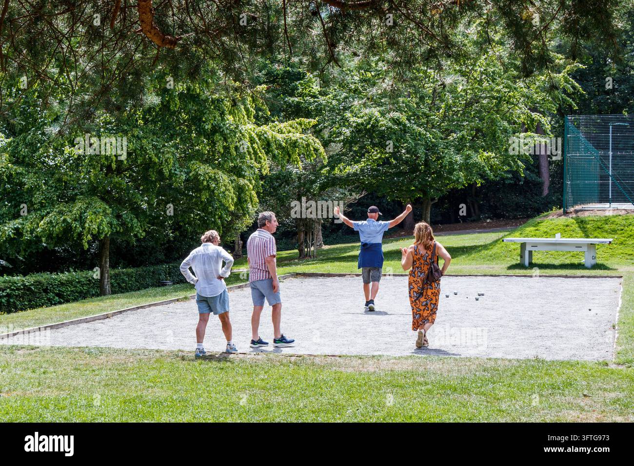 Ein Mann gestikuliert in einer Gruppe von vier Personen, die ein Spiel Petanque oder Boule auf einem öffentlichen Kiesplatz in Waterlow Park, London, UK, spielen Stockfoto