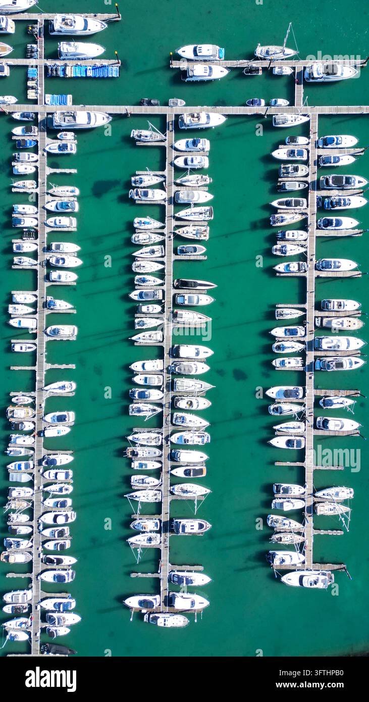 Luftaufnahme des Torquay Harbour mit Reihen von weißen Motorbooten und Yachten, die an Holzstegen im türkisfarbenen Wasser der Marina in Torquay vertäut sind, E Stockfoto