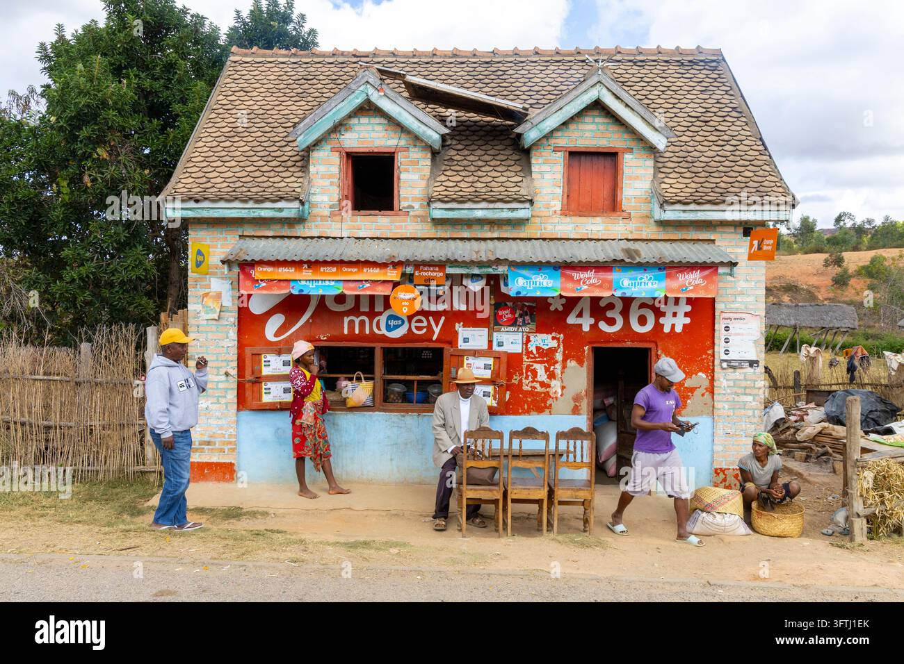 Dorfbewohner versammelten sich vor einem kleinen Straßendorfgeschäft mit bunten Werbeschildern, Vakinankaratra, Antsirabe, Madagaskar Stockfoto