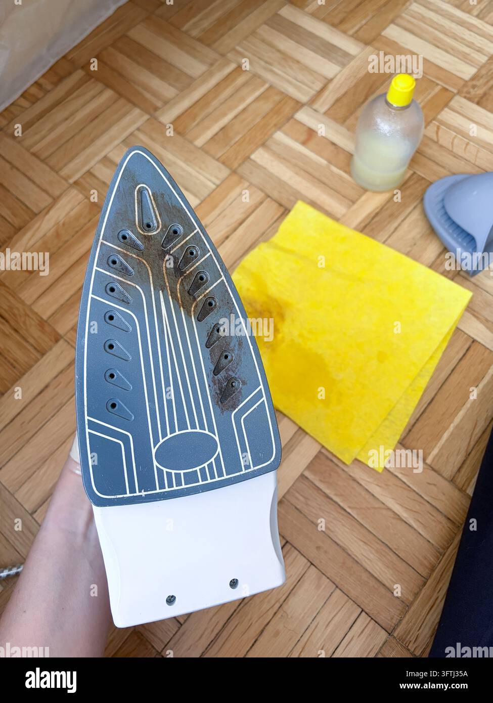 Reinigung von verbrannten Rückständen von einem Kleiderbügeleisen mit Zitronensäure und einem gelben Tuch zu Hause Stockfoto