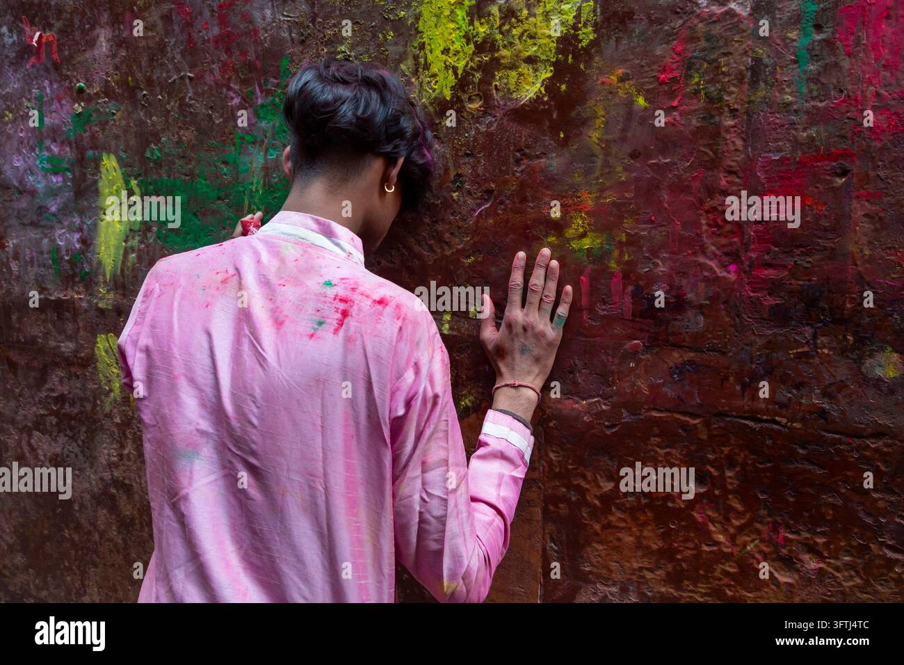 Rückansicht einer Person in einem mit rosa Puder befleckten Kurta, die eine Hand stützt, Uttar Pradesh, Vrindavan, Indien Stockfoto