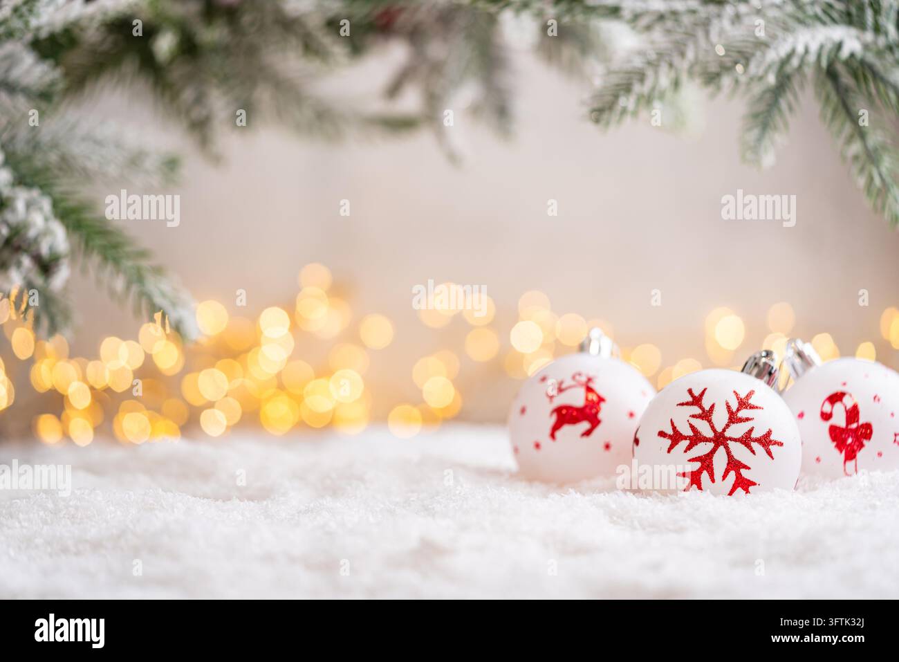 Ein Weihnachtshintergrund mit weißen, handbemalten Kugeln mit einem roten Rentier, Schneeflocke und Zuckerstange unter gefrorenen Kiefern im Schnee, sanft beleuchtet von warmen funkelnden Lichtern mit Kopierraum. - Fotomontage Stockfoto