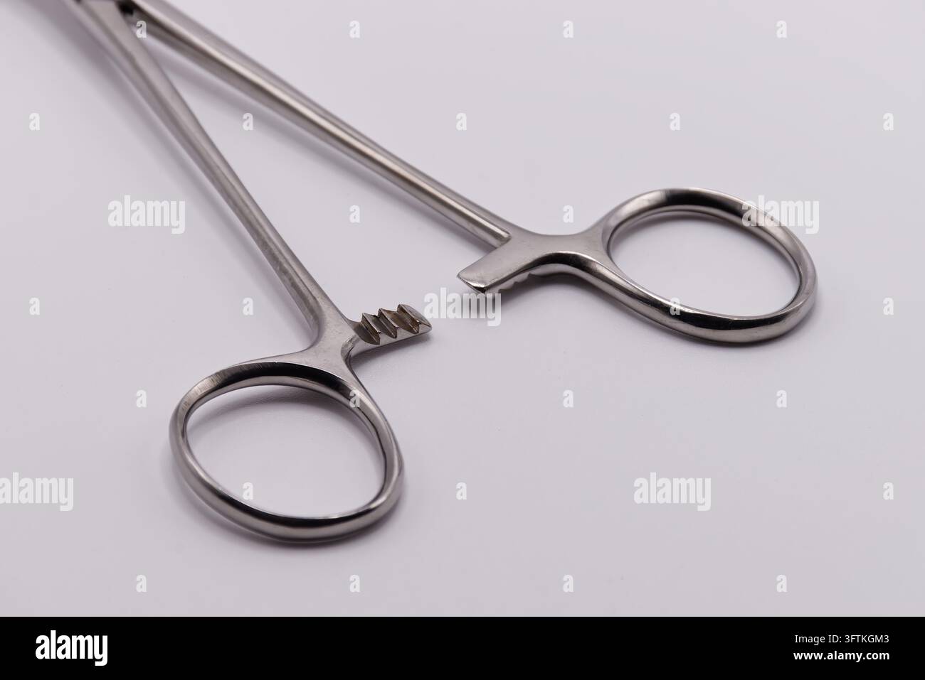 Nahaufnahme der Griffe und des Verriegelungsmechanismus von chirurgischen Edelstahlzangen, isoliert auf weißem Hintergrund. Stockfoto