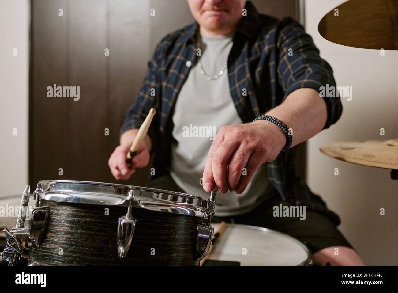Männlicher Musiker stimmt eine Snaredrum während der Proben einer Rockband Stockfoto