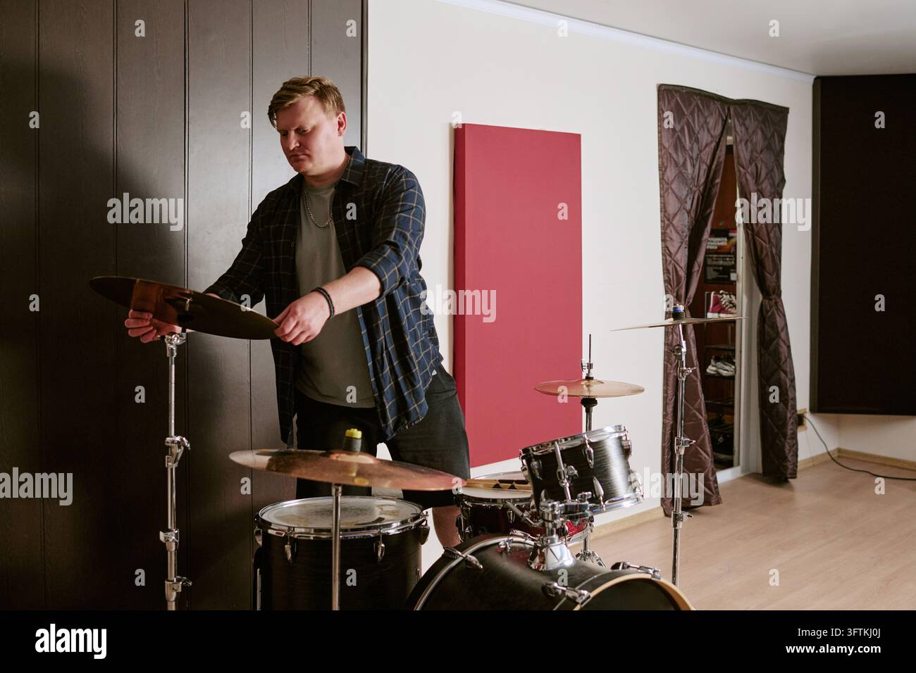 Mann stellt Schlagzeug für die Probe im Musikstudio ein Stockfoto