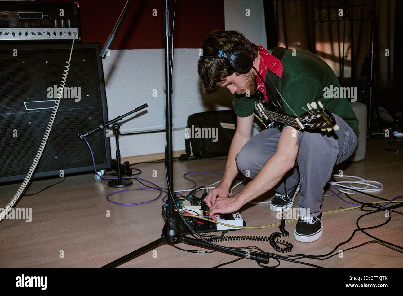 Musiker, der ein Gitarreneffektpedal in einem Aufnahmestudio einstellt Stockfoto