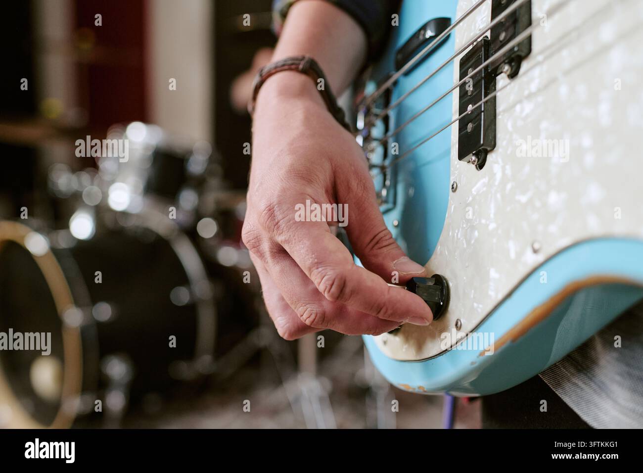 Musikerhand, die den Lautstärkeknopf an der Bassgitarre einstellt Stockfoto