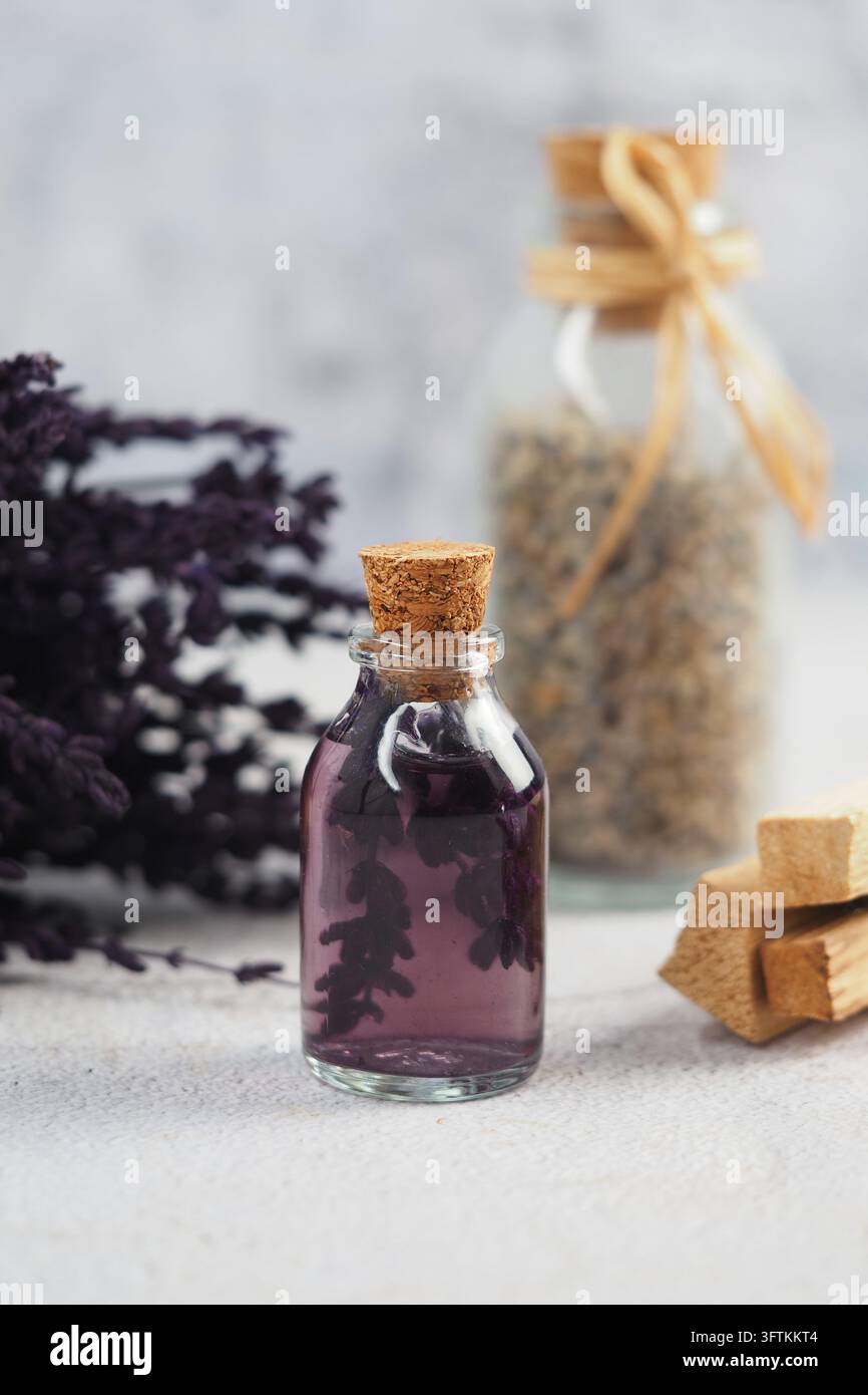 Lavendelwasser in einer kleinen Flasche mit trockenen Lavendelflora in der Nähe Stockfoto