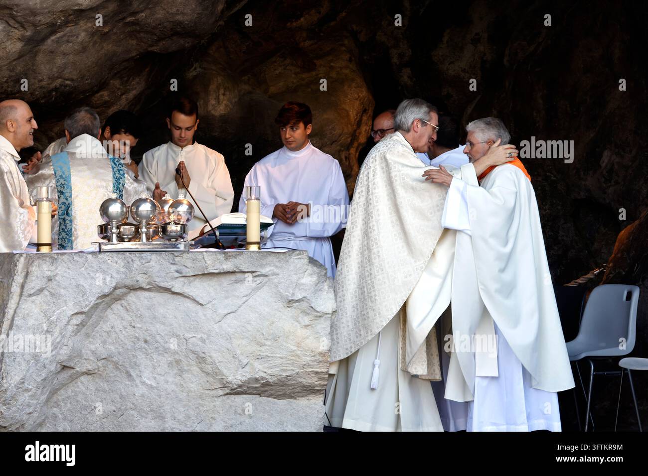 Mehrere katholische Priester zelebrieren eine feierliche Messe vor einem grob behauenen Steinaltar, der sich in der heiligen Grotte der Erscheinungen in Massabi befindet Stockfoto