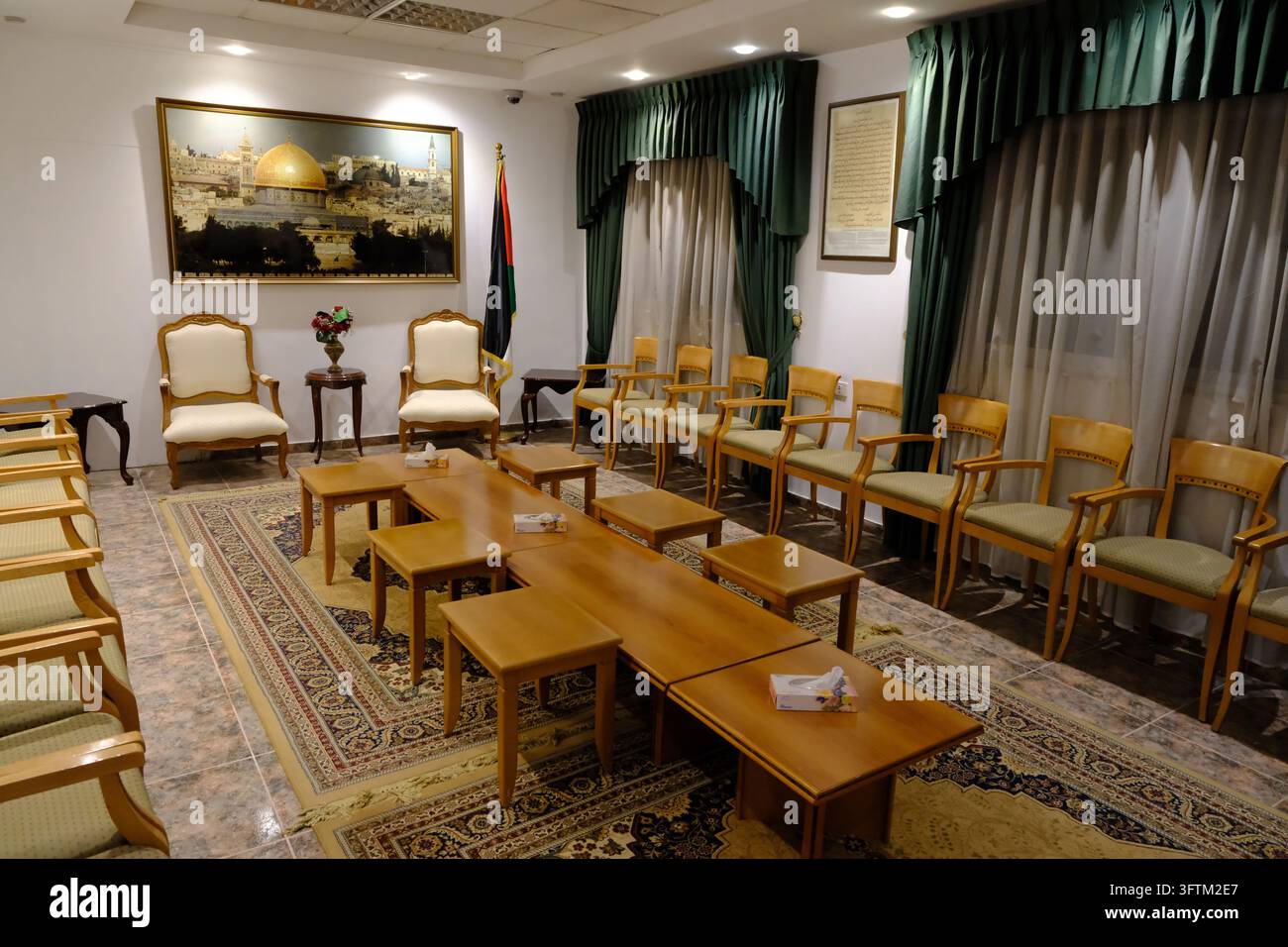 Ein rekonstruiertes Empfangszimmer im Yasser-Arafat-Museum in Ramallah mit Holzstühlen, Kaffeetischen, Teppichen und einer palästinensischen Flagge. Stockfoto