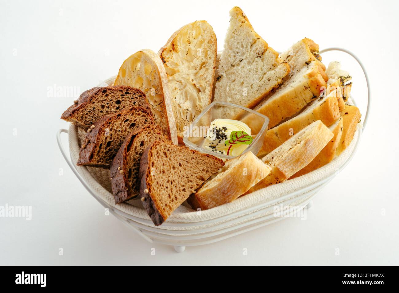 Korb mit verschiedenen geschnittenen Brotsorten mit Butter auf weißem Hintergrund Stockfoto
