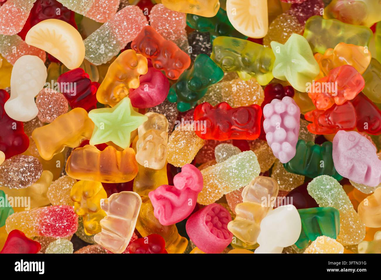 Kreativer Hintergrund aus Gummibärchen. Minimales trendiges Gummies-Konzept. Gelee-Süßigkeiten-Ästhetik. Buntes Flat Lay. Top-Down-Hintergrund. Stockfoto