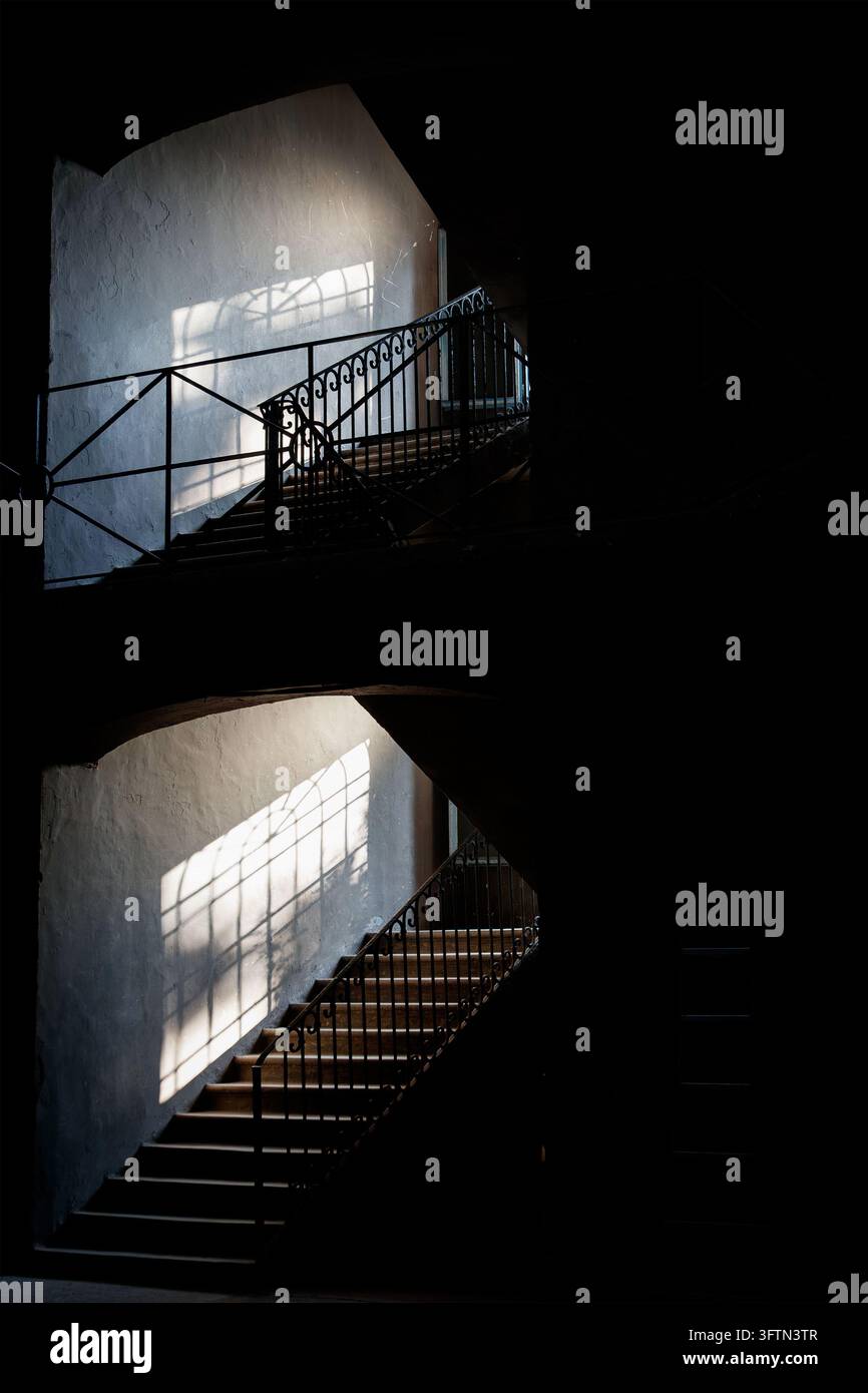 Helle und dramatische Schatten auf einer Gefängnisinnentreppe mit Geländern im Gebäudeinneren Stockfoto