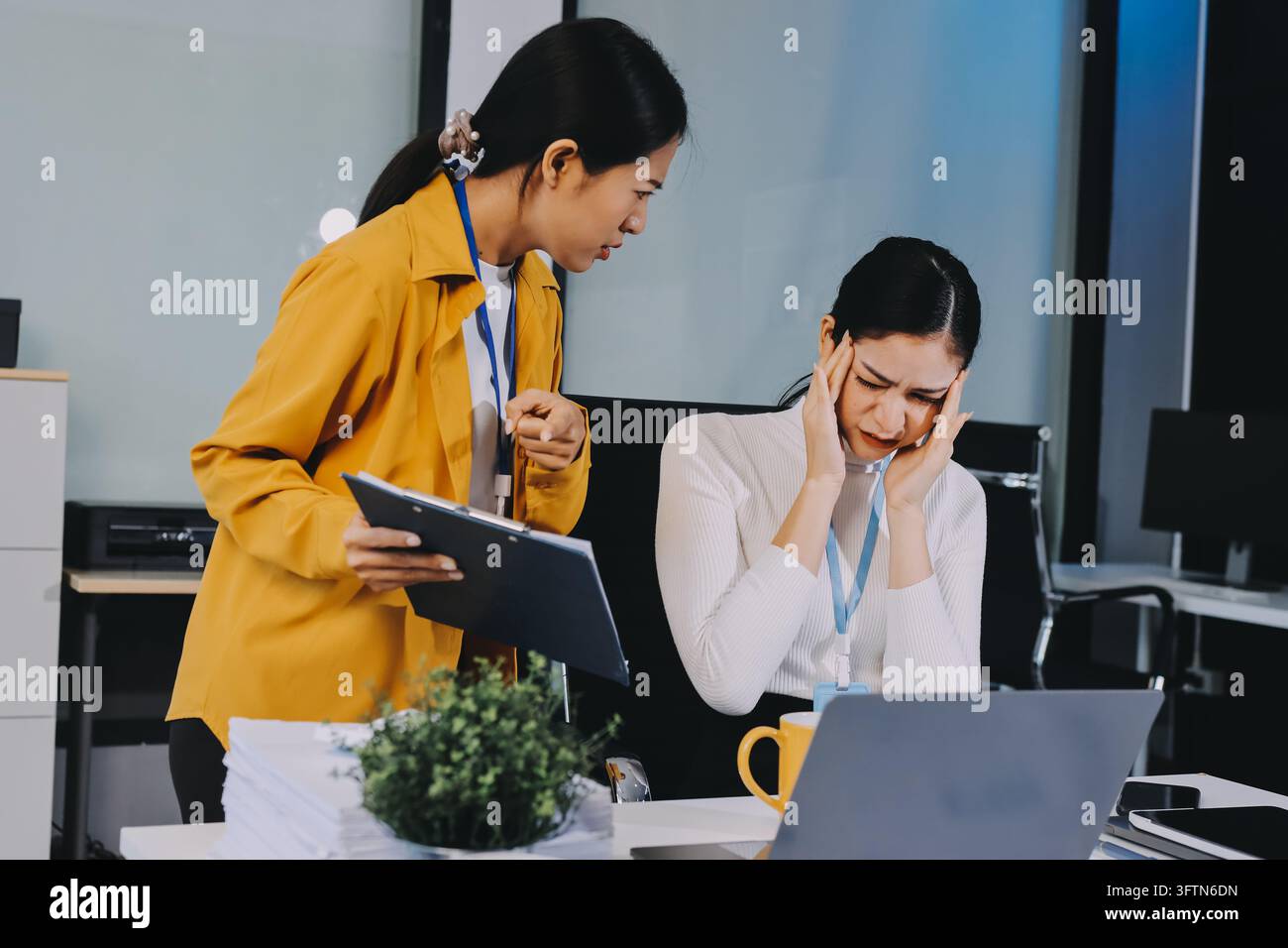 Zwei asiatische Geschäftsfrauen stehen im Büro unter Stress und Kopfschmerzen, fühlen sich durch den Arbeitsdruck erschöpft und konzentrieren sich auf psychische Gesundheit und Stressmanagement Stockfoto