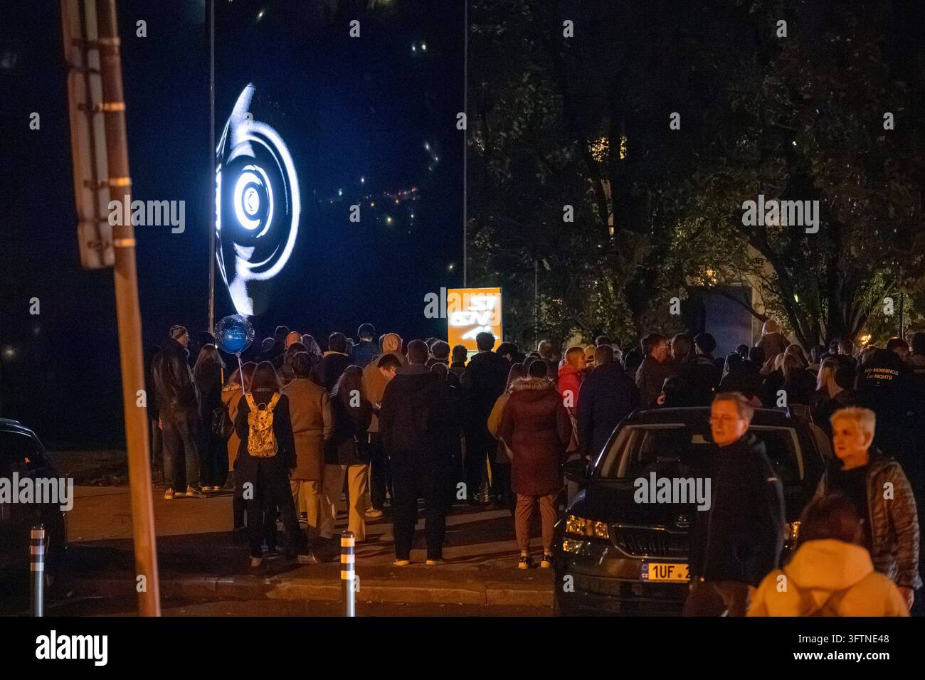 Festbesucher beobachten abstrakte kreisförmige Visuals, die auf eine große digitale Kunstinstallation beim Signal Festival 2026 projiziert werden. Stockfoto