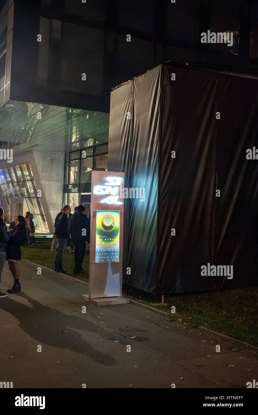 Ein beleuchtetes Schild des Signal Festival 2026 und ein Event-Poster stehen neben einer großen temporären Struktur vor einem modernen Gebäude. Prag, Tschechische Republik Stockfoto