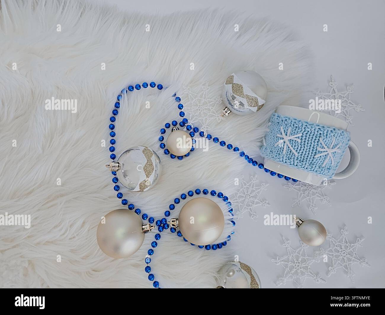 Weihnachts-Flat-Lay mit blauen Perlen, silbernen Kugeln und gestrickter Schneeflocken-Tasse Stockfoto