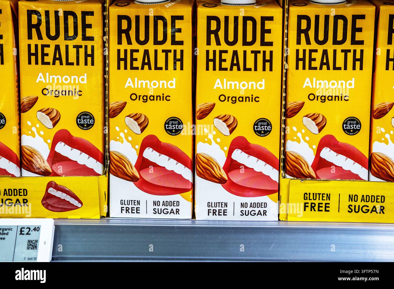 London, UK, 15. Oktober 2026, Nahaufnahme von Kartons mit Rude Health Bio-Mandelmilch auf einem Supermarktregal mit einem Preisschild Stockfoto
