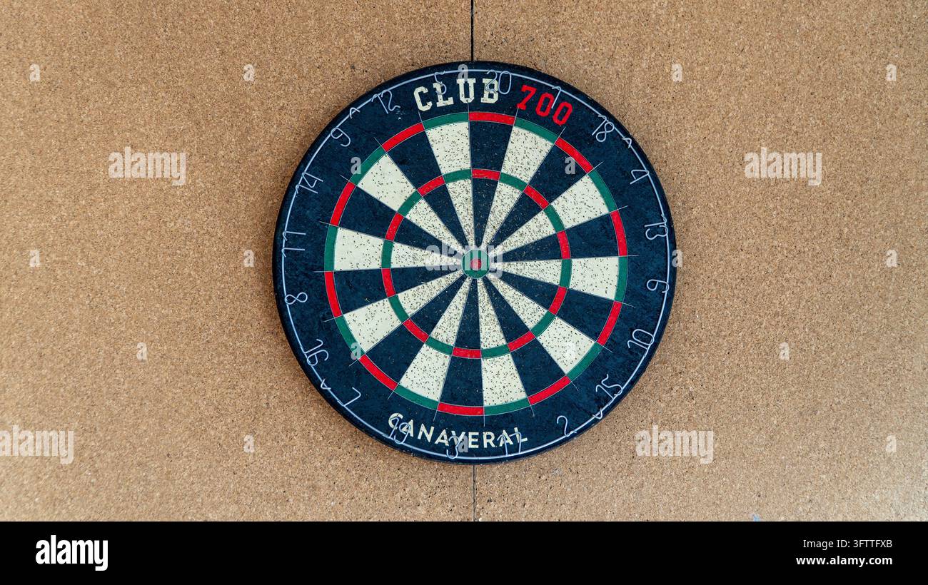 Dartscheibe an einer Korkwand mit schwarzen, weißen, roten und grünen Segmenten und einem nummerierten Ring, bereit für ein Dartspiel Stockfoto