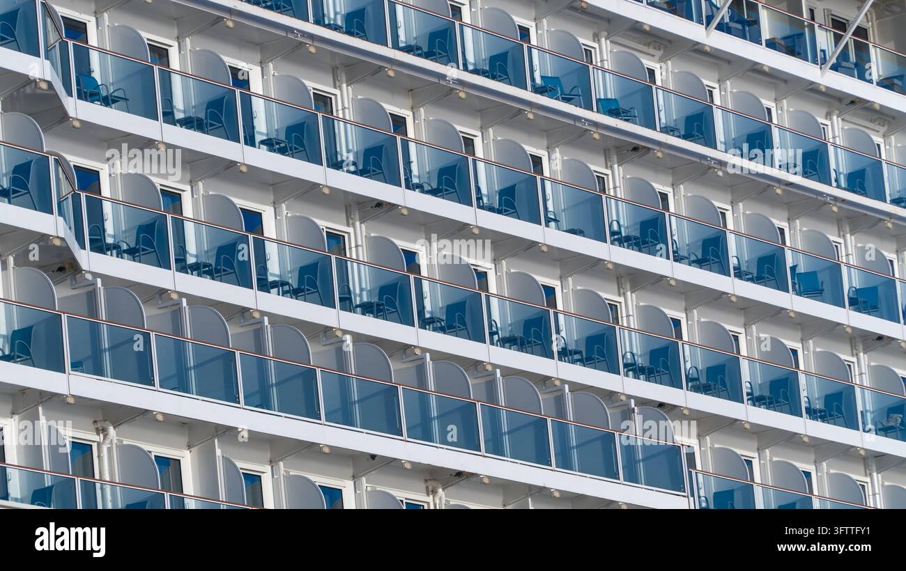 Balkone eines Kreuzfahrtschiffes in weißen Reihen auf der Aufbauten eines großen Kreuzfahrtschiffes, schräg gesehen, mit Stühlen und Tischen auf den privaten Balkonen Stockfoto