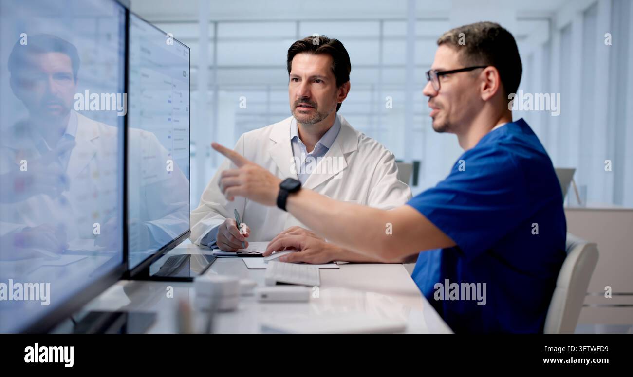 Zwei hispanische Ärzte überprüfen selbstbewusst KI-Medizinische Notizen auf dem Computerbildschirm. Stockfoto