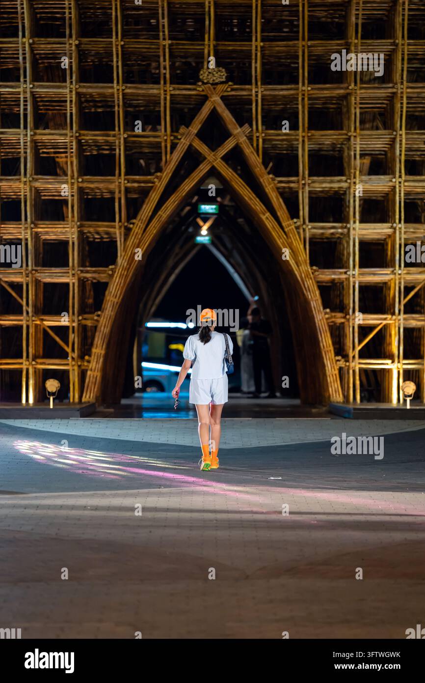 Grand World, Phu Quoc, Vietnam - 16. April 2026: Ein Besucher geht auf den Eingang einer großen beleuchteten Bambusarchitekturinstallation zu in der Stockfoto