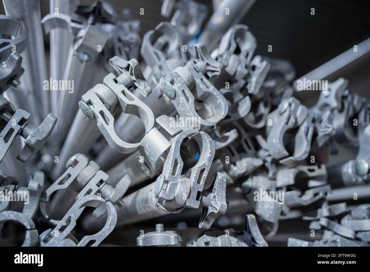 Metallrohrklemmen mit Scharnierbacken und gewindelten Drehgriffen, die an Rohrprofilen befestigt sind, zeigen wiederverwendbare Verbindungshardware für temporäre Str. Stockfoto