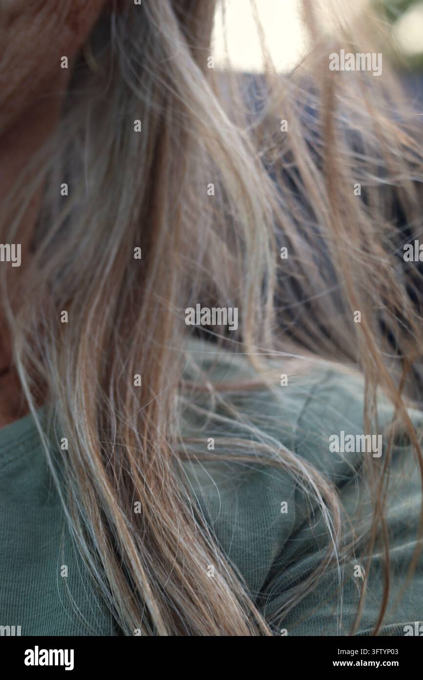Nahaufnahme einer reifen Frau mit langem grauem und blondem Haar, das im Wind draußen weht Stockfoto