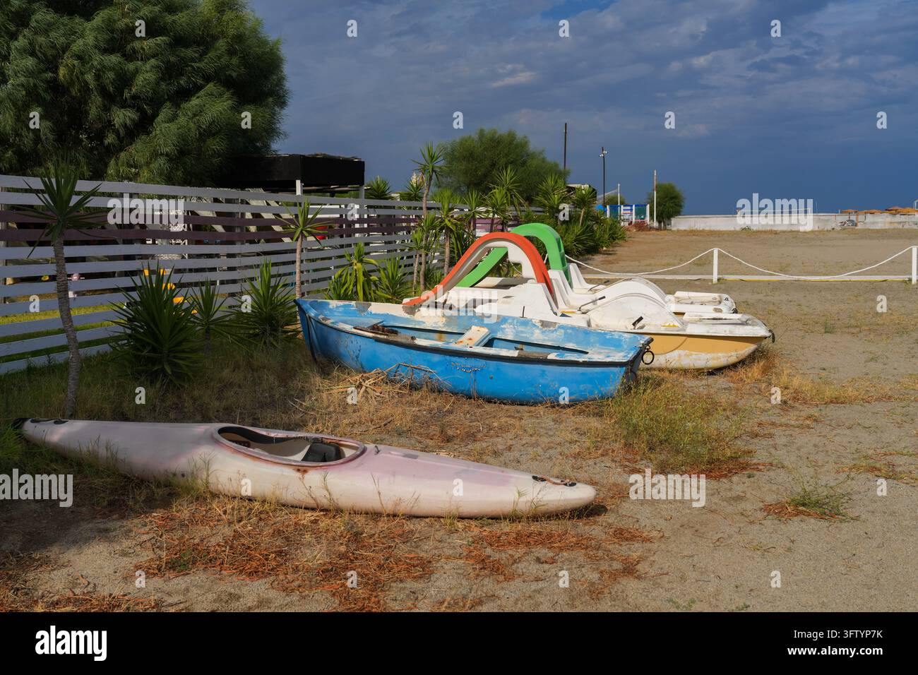 Alte Tretboote, Ruderboot und Kajak am leeren Strand am Ende der Saison, Kalabrien, Italien Stockfoto
