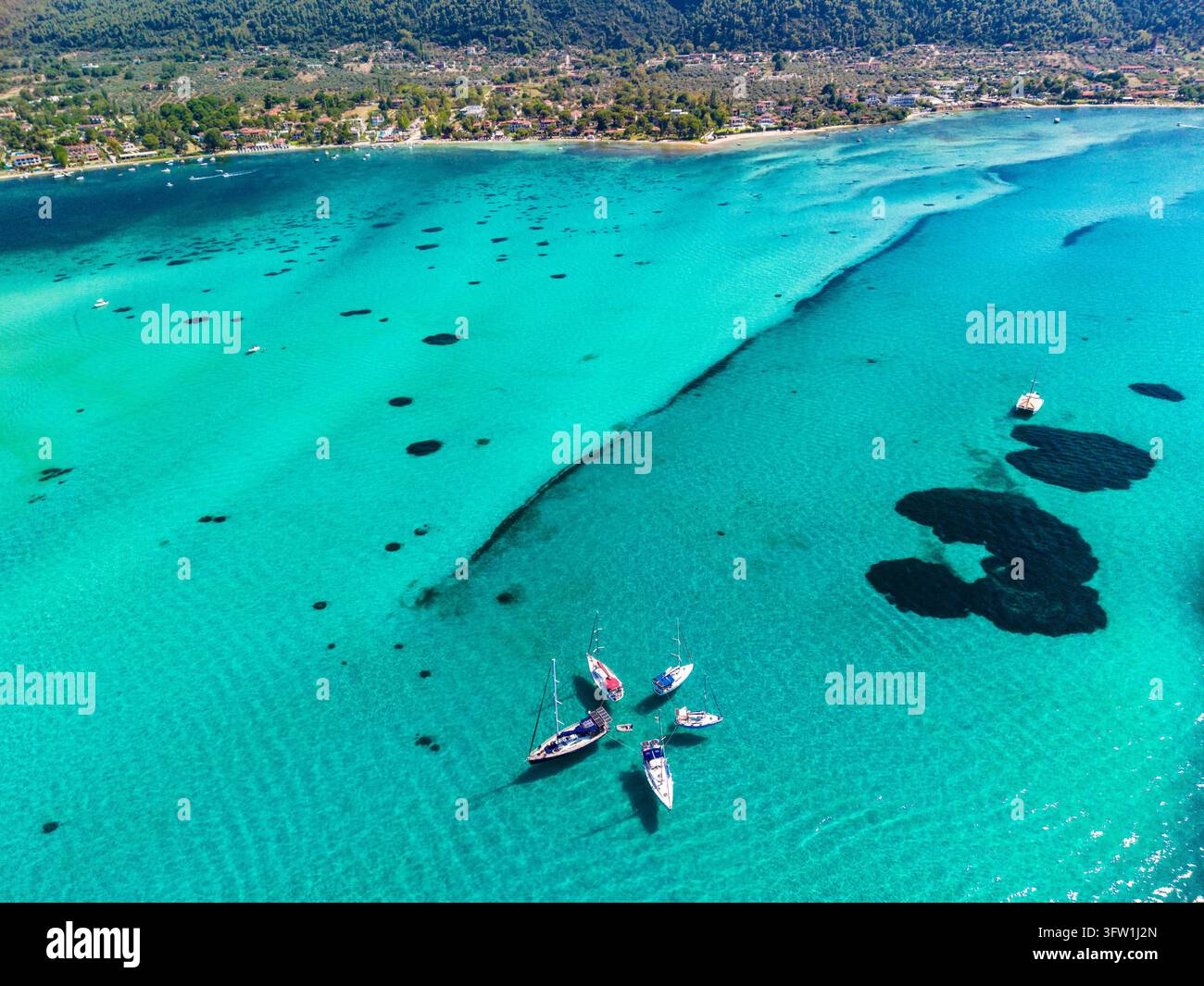 Fünf Segelboote, die in der Nähe des Blue-Lagoon-Strandes in Chalkidiki, Griechenland, festgemacht sind Stockfoto