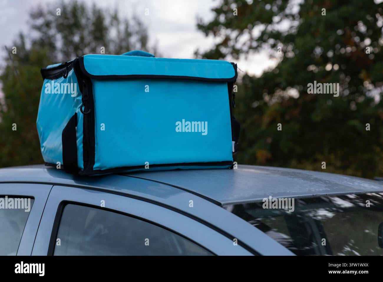 Blaue thermische Lebensmittellieferungstasche auf dem Dach eines Autos für den Kurierdienst platziert Stockfoto