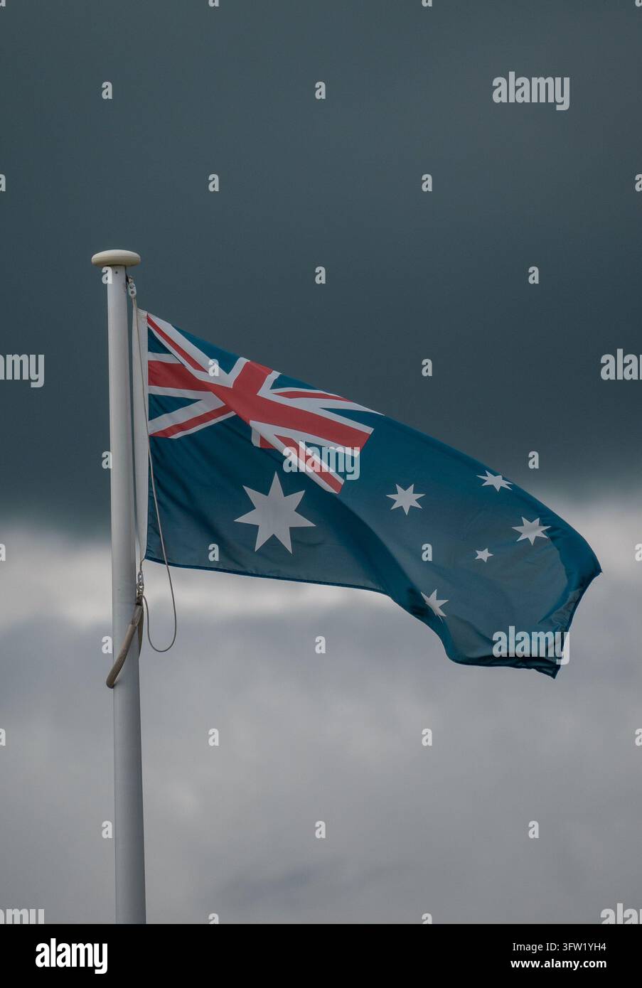 Australische Nationalflagge weht an einer Flaggenstange vor einem dunklen stürmischen Himmel, Perth, Westaustralien Stockfoto