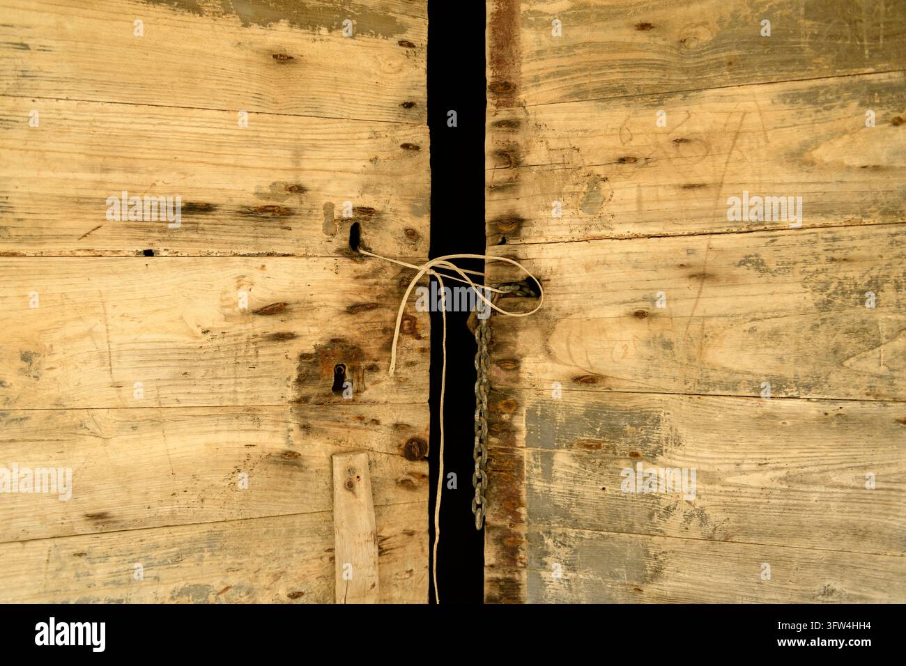 Alte Holzbretter mit einem schmalen Spalt und einem einfachen Schnurbinder, die eine abgenutzte rustikale Textur zeigen. Stockfoto