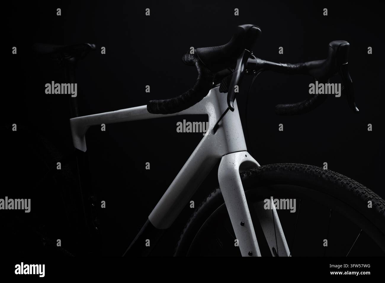Modernes Carbon-Gravel-Fahrrad in dramatischer Schräglicht-Belichtung vor schwarzem Hintergrund. Stockfoto