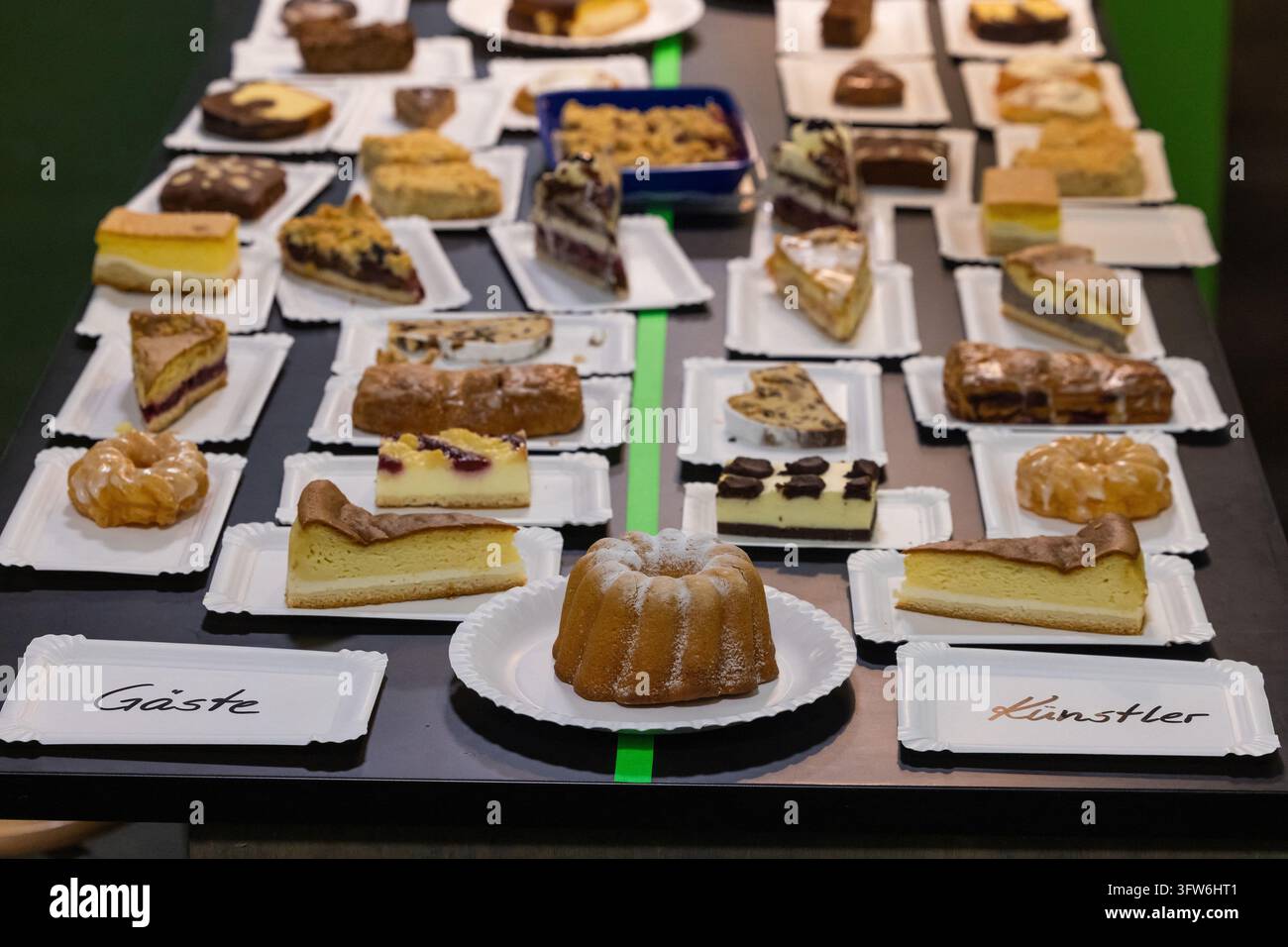 Dresden, Deutschland. 18. Okt., 2026. Zahlreiche Kuchenstücke sind auf einem Tresen beim 4. Kuchenkonzert im Hygienemuseum in Dresden ausgestellt. Dieses ungewöhnliche Konzert wird vom Institut für gute Laune organisiert. Jeder Gast bringt zwei Stücke Kuchen als Eintritt mit, die dann nach dem Konzert gemeinsam von Gästen und Künstlern gegessen werden. Die Organisatoren sehen das Kuchenkonzert als ein soziales Kunstprojekt an, das darauf abzielt, ein neues Gemeinschaftsgefühl zu fördern. Credit: Jürgen Lösel/dpa/Alamy Live News Stockfoto