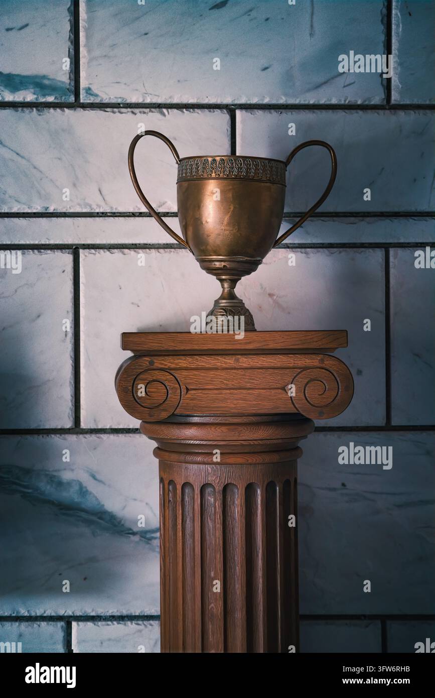 Vintage-Bronzetrophäe steht auf einem hölzernen ionischen Podest vor einer Marmorfliesenwand Stockfoto